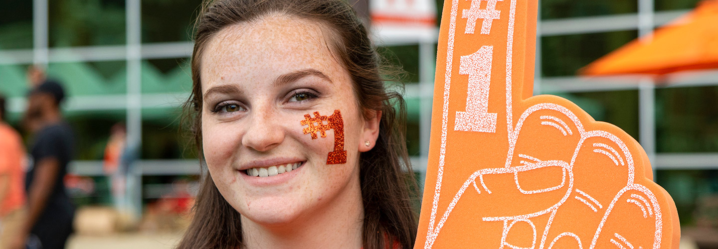 A student showing her pride to be a warrior displaying a foam number one sign