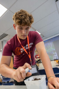 student spraying a bin of compost