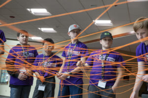students holding an interconnected web of string