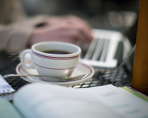 Person working at a laptop with a cup of coffee