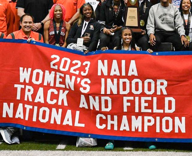 photo of 2023 women's track and field team with championship banner