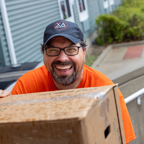 A dad laughing as he carries a box to the dorm