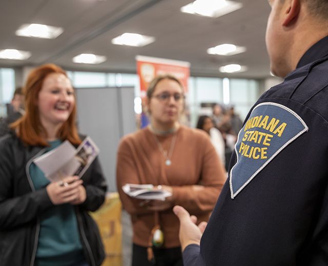two students talking to a police officer at CJ career fair