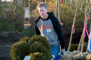 President Karl W. Einolf pushing a wheel barrel of bushes for Habitat for Humanity