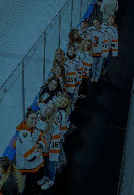 Students in jerseys watching the Hockey Orange Out game