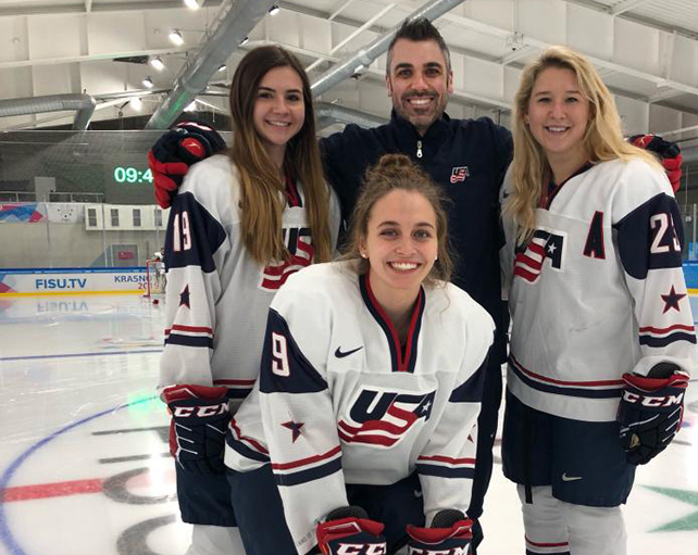 a male, Scott Hicks, the first coach for Indiana Tech's women's hockey, is seen with three female players from the US National team