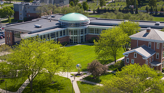 An aerial view of a Snyder Academic Center with a distinctive green dome surrounded by lush green lawns, trees, and pathways.