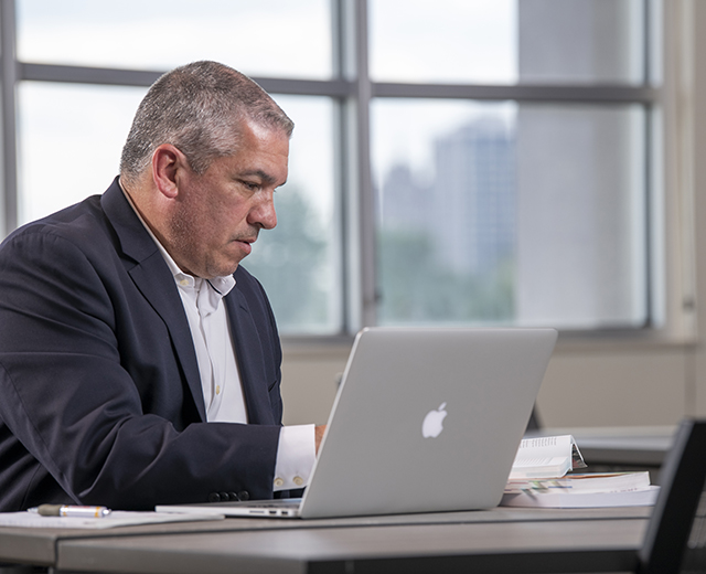 man studying with books and laptop computer
